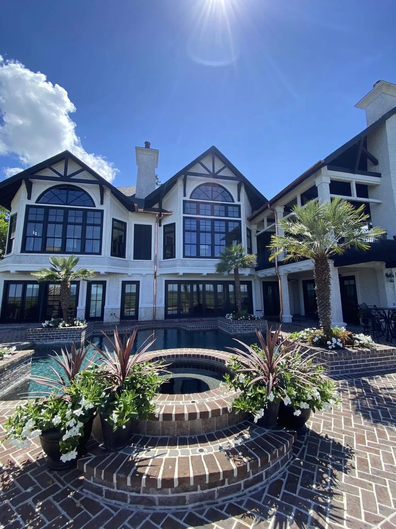 Large home with gutters along several rooflines above a pool courtyard