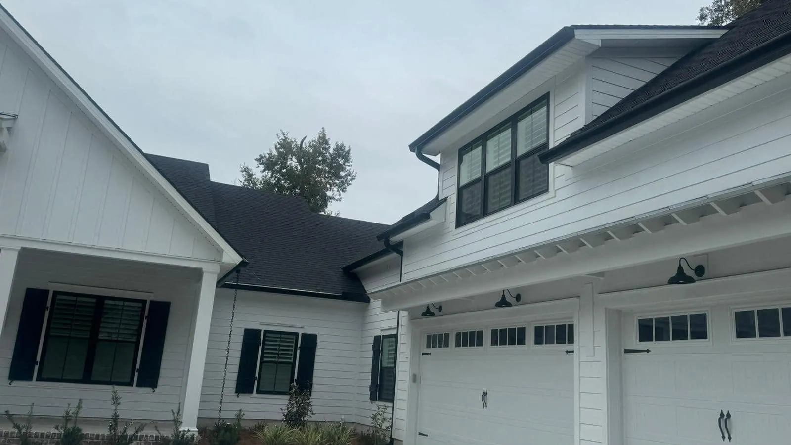 White farmhouse-style home with new white gutters over the garage